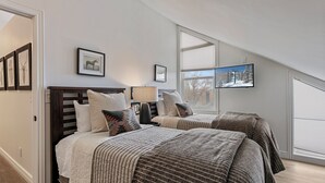 Ein Schlafzimmer mit zwei Betten, einem großen Fenster und gerahmten Bildern an der Wand.