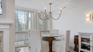 Ein Essbereich mit einem runden Tisch, zwei Stühlen, einer Chandelüster und einer Bücherwand.