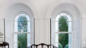 A room with a large bed, two arched windows, and a radiator.