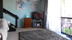 Ein Schlafzimmer mit einem großen Bett, einem Fernseher, einem Schminktisch und einem Bild an der Wand.