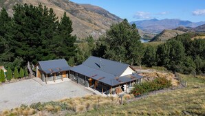 Una casa moderna con techo metálico, rodeada por un paisaje natural con montañas y árboles.
