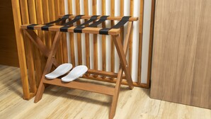 A wooden shoe rack with straps holding white shoes against a wooden wall. - Sukhon Hotel (Bangkok)
