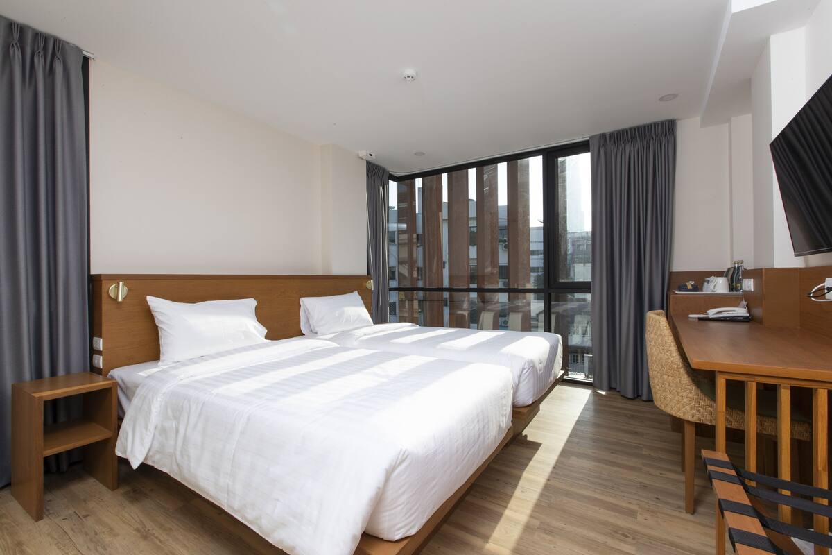 A hotel room with a large bed, a desk, and a chair.