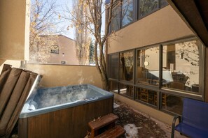 A hot tub in a covered outdoor area with a view of a building and trees.
