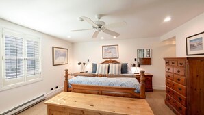 Ein Schlafzimmer mit einem hölzernen Bett, einem Nachttisch, einer Kommode und einem Deckenventilator.