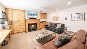 Ein Wohnzimmer mit Kamin, einer Couch, einem Couchtisch und Holzschränken.