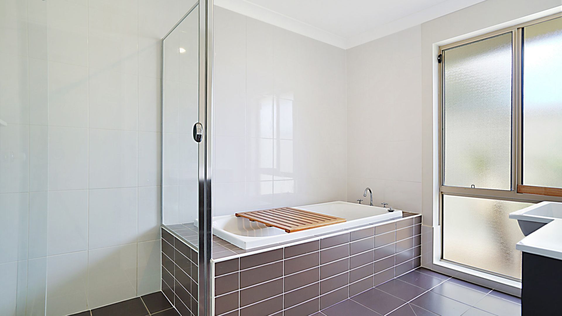 Een moderne badkamer met een douchecabine van glas, een vrijstaand bad en een groot raam voor natuurlijk licht.