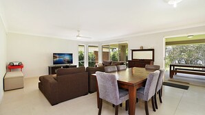 Un salón amplio con una televisión grande, asientos cómodos y una zona de comedor.