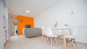 A modern dining area with a white table and chairs, a grey sofa, and a TV on the wall. - Rent Venezuela CA5 (Córdoba)