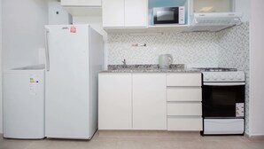 A compact kitchen with white appliances, including a refrigerator, microwave, and oven. - Rent Venezuela CA5 (Córdoba)