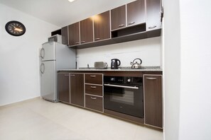 Una cocina moderna con electrodomésticos de acero inoxidable, armarios de madera y un reloj de pared.