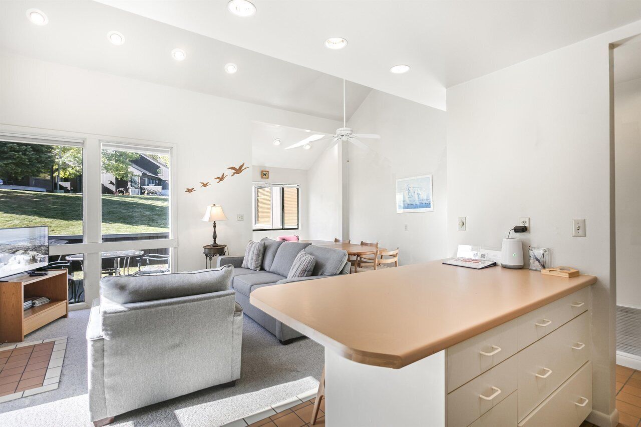 Una sala de estar moderna con un sofá, una mesa de centro y un televisor. Hay una zona de comedor con una mesa y sillas.
