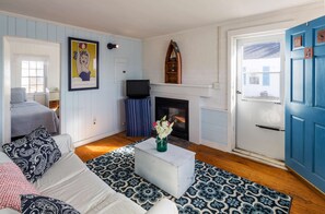 A living room with a sofa, a television, a fireplace, and a door.