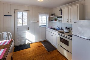 A kitchen with white cabinets, a stove, a sink, and a refrigerator.