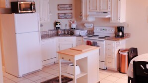 A compact kitchen with white cabinets, a microwave, a stove, and a coffee maker. - Cozy BeachFront Condo with Oversized Balcony and Amazing Views (South Padre Island)