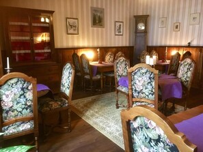 Un coin repas avec des chaises et des tables en bois, un tapis à motifs et des tableaux encadrés accrochés au mur.