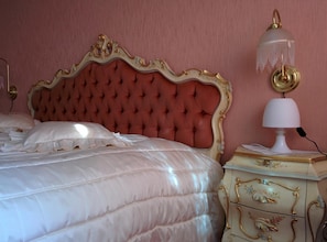 Un lit avec une tête de lit capitonnée, une lampe de chevet et une table de chevet avec des tiroirs.