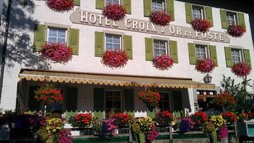 A hotel with a white facade, green shutters, and multiple flower baskets.