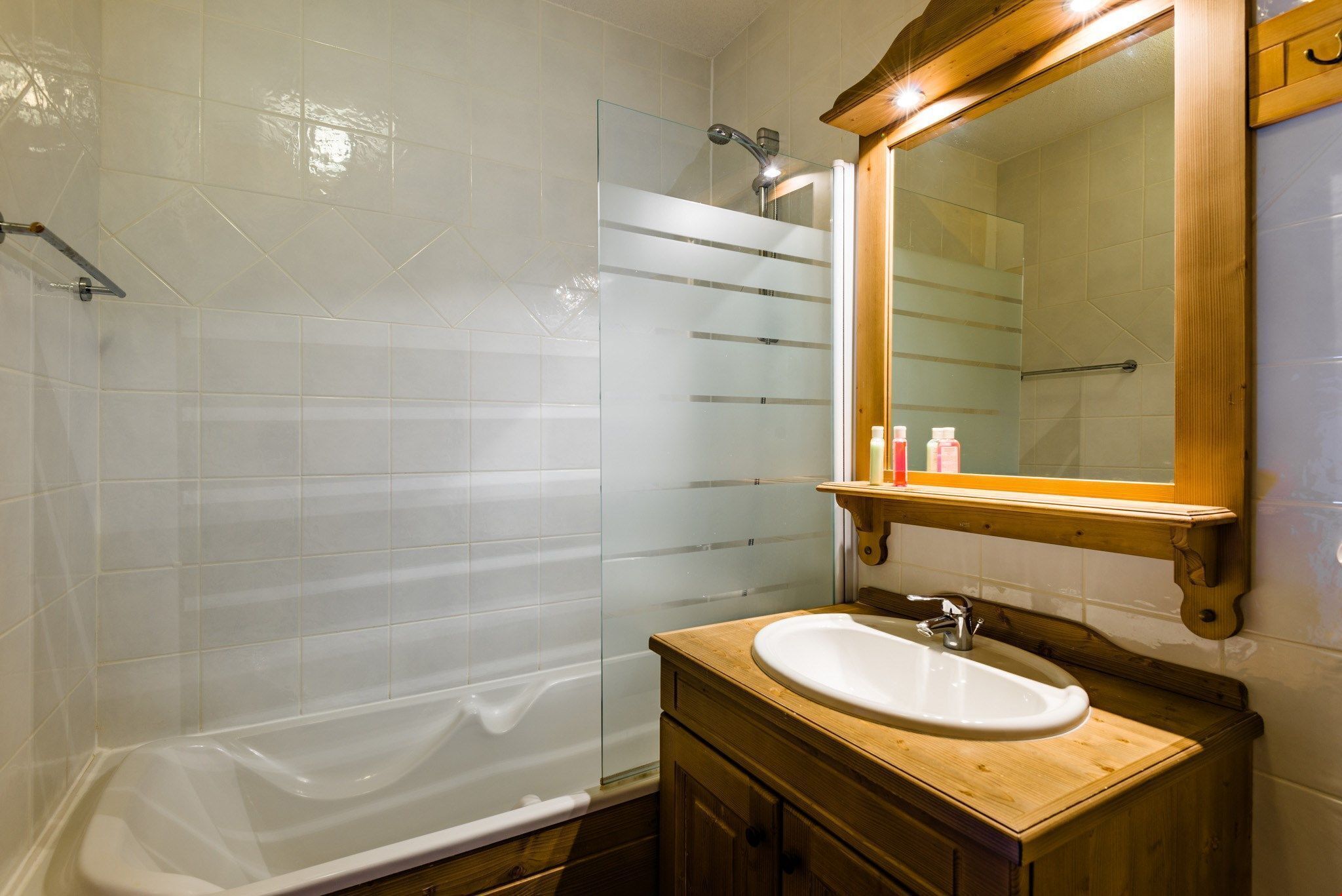 Une salle de bain avec une baignoire, un meuble-lavabo en bois et un miroir.