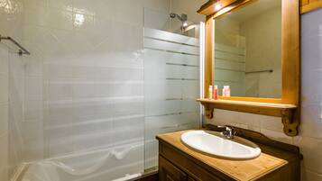 Une salle de bain avec une baignoire, un meuble-lavabo en bois et un miroir.
