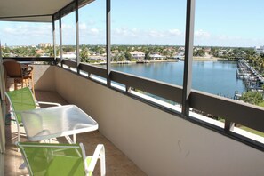 En balkon med udsigt over en sø, et bord og stole.