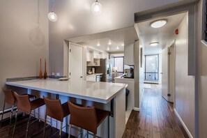 Cozinha moderna com ilha central, banquetas e iluminação pendente.