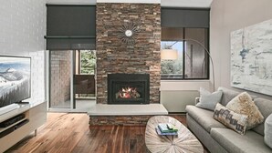 Ein modernes Wohnzimmer mit Kamin, Fernseher, Sofa und Couchtisch.