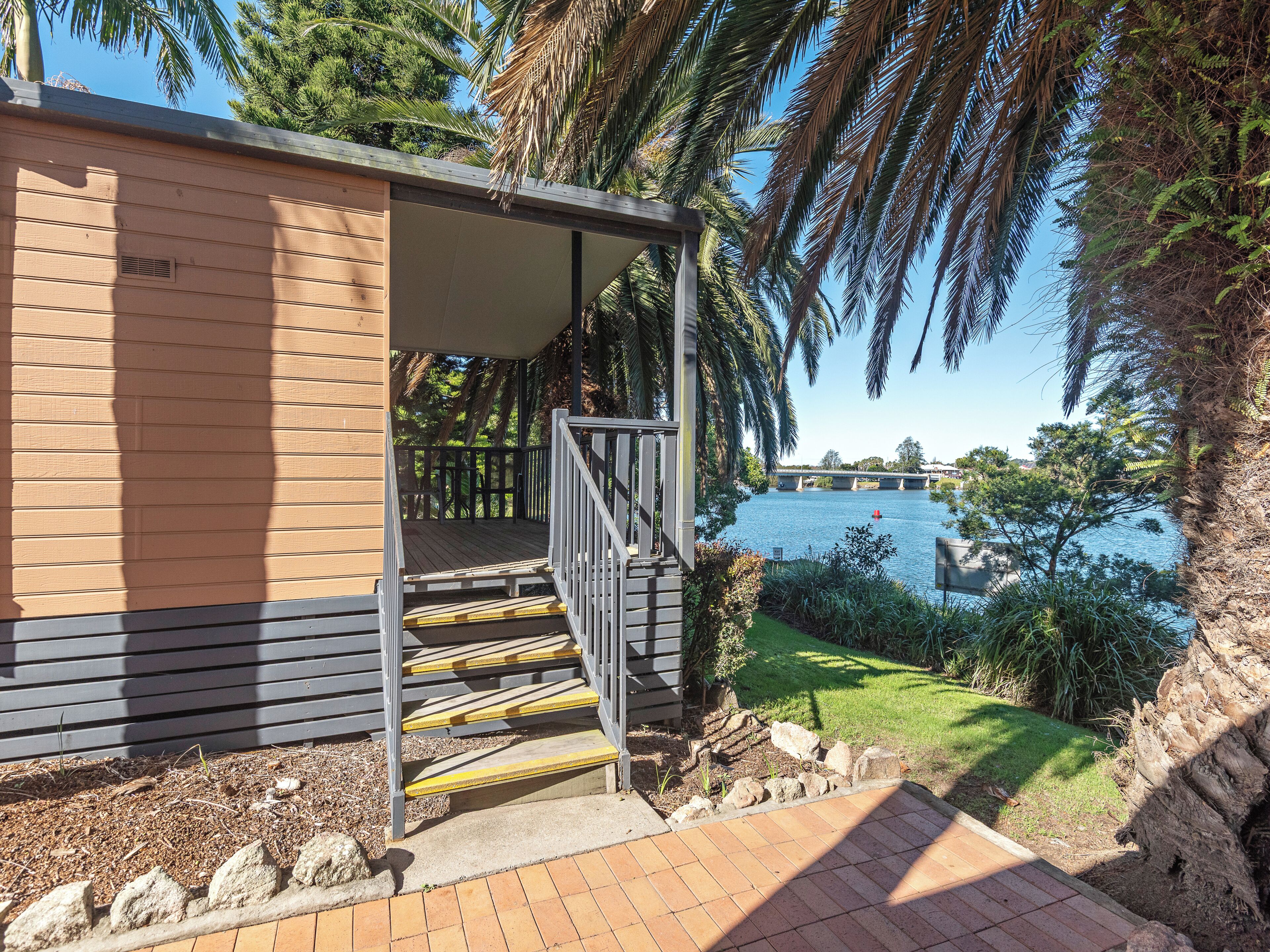 A covered outdoor area with a wooden deck and steps leading to a building with a sloped roof.