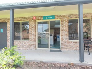 A brick building with a green sign indicating a laundry facility. There is a wheelchair-accessible door on the left. - Moruya Holiday Park (Moruya)