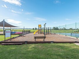 Ein Spielplatz mit Rutsche, Schaukeln und einer Bank.