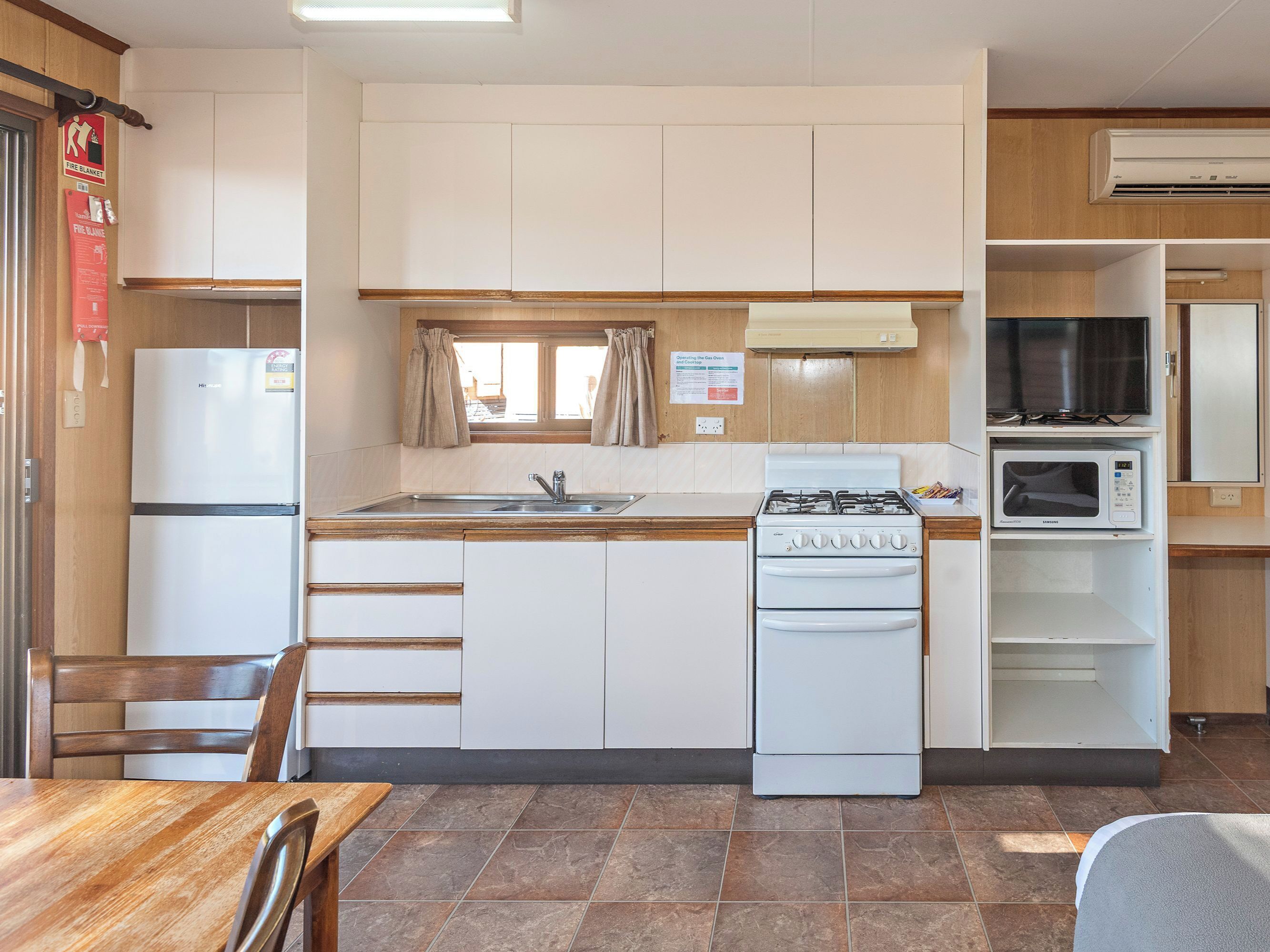 Una cocina compacta con estufa a gas, microondas y un lavamanos.