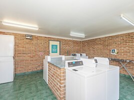 A laundry facility with multiple washing machines, a 'Staff Only' sign, and a no-smoking sign on the wall.