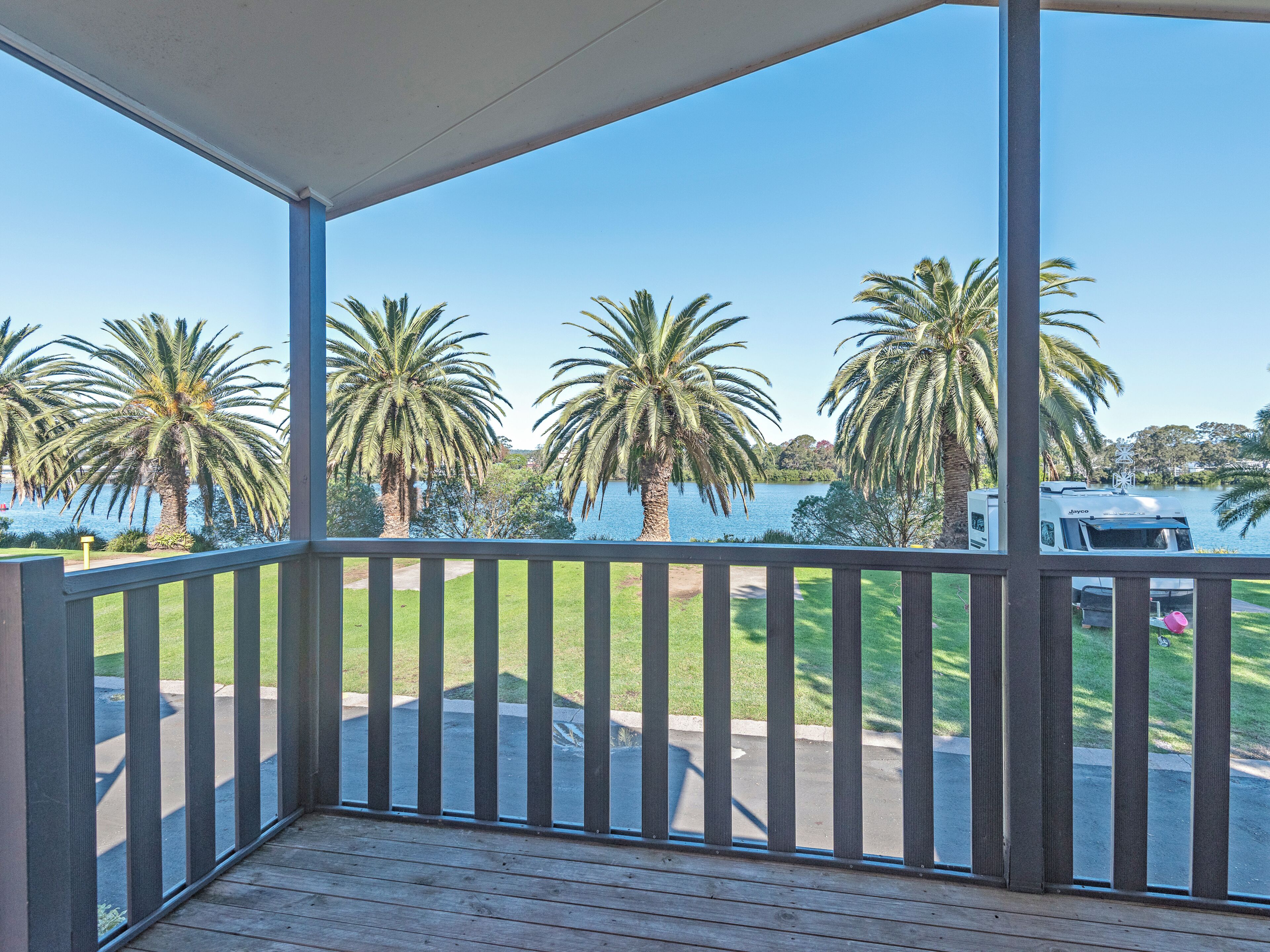 A covered outdoor area with a view of a lake and palm trees.