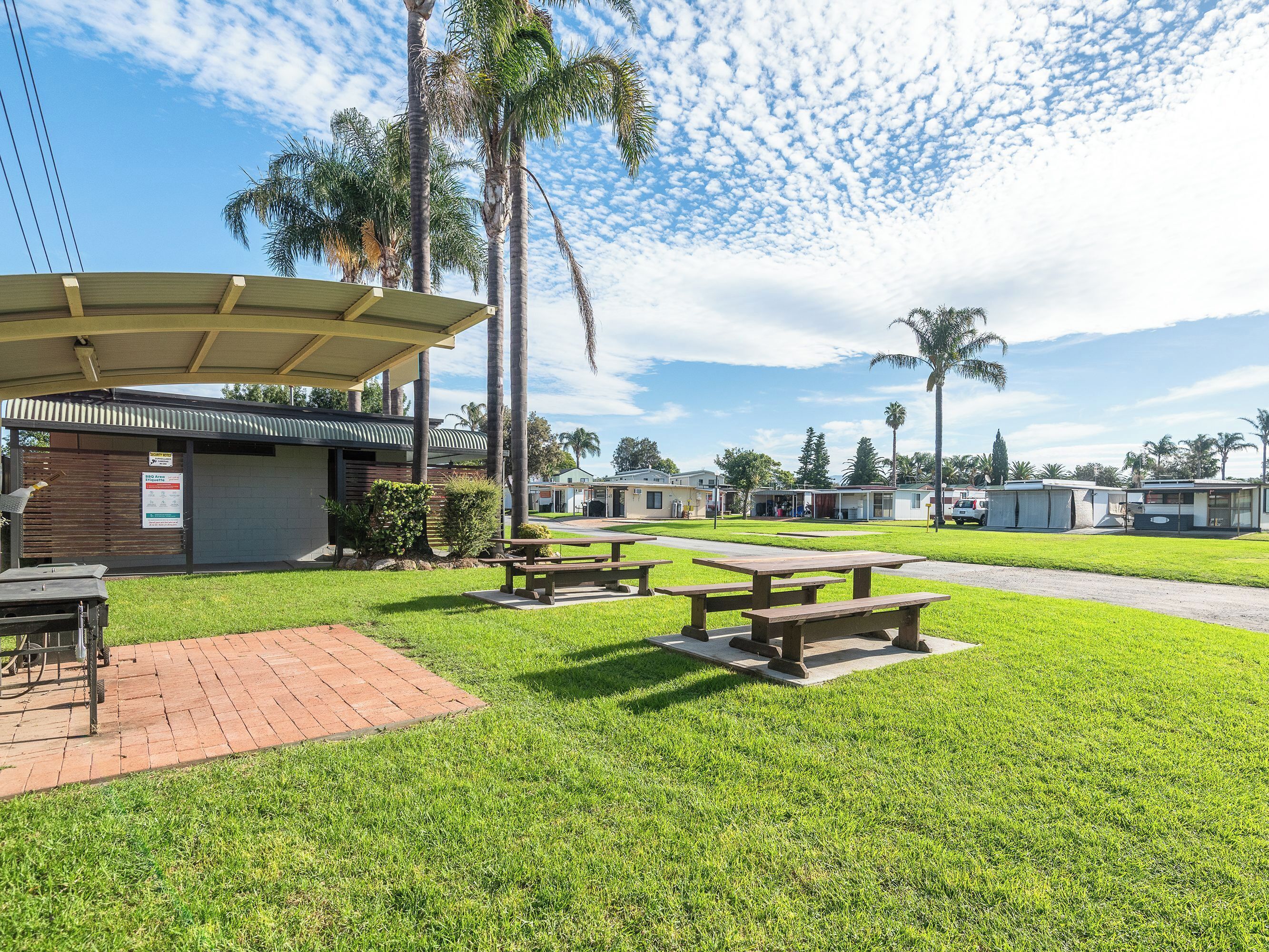 A grassy outdoor area with picnic tables and a covered shelter.