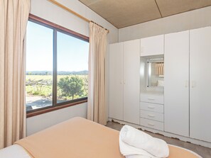 A bedroom with a large window, a bed, a wardrobe, and a mirror. - Moruya Holiday Park (Moruya)