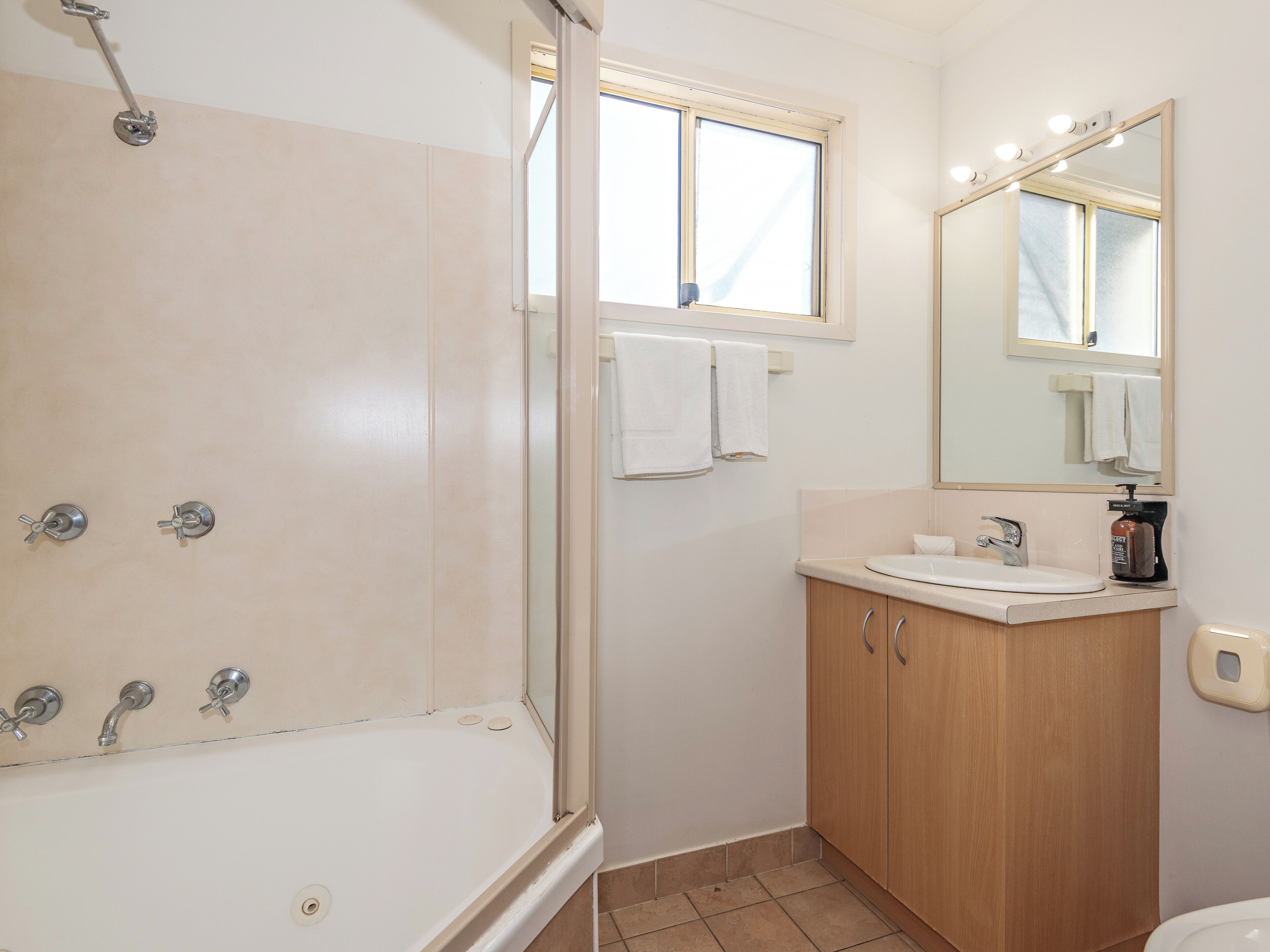 Une salle de bain avec une baignoire, un lavabo, un miroir et une fenêtre.