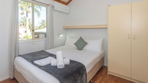 Une chambre à coucher comprenant un lit, une armoire, une fenêtre avec des rideaux et un appareil de climatisation.