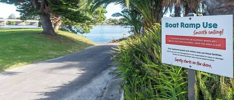 A sign for a boat ramp use area with safety warnings and a reminder to keep the area clear.