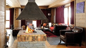 A cozy living room with a fireplace, leather furniture, and a stone fireplace surround.
