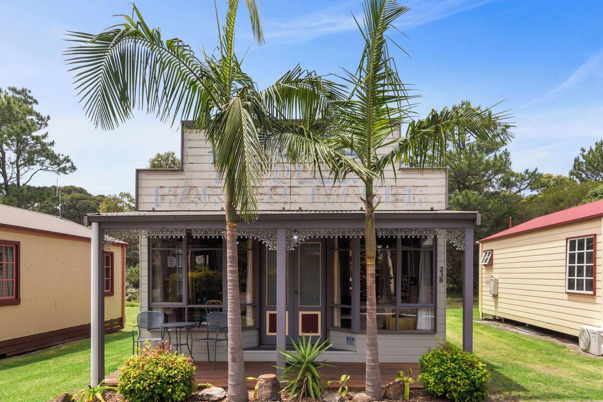 A two-story building with a porch, palm trees, and a small garden.