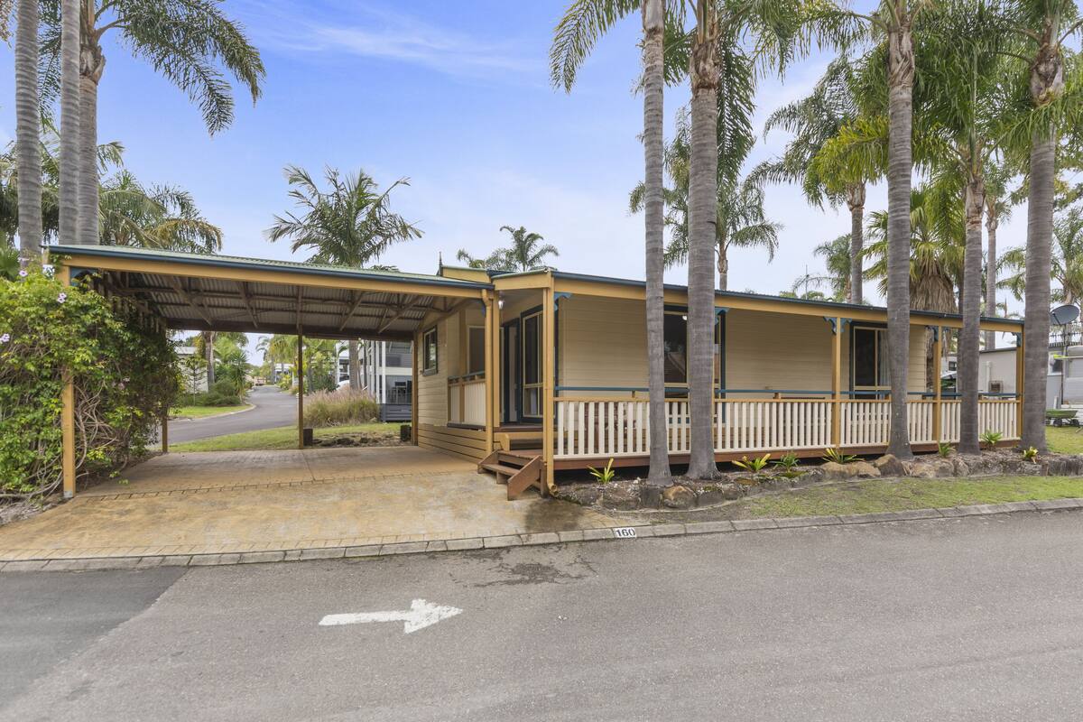 A single-story mobile home with a covered porch and a small front yard.