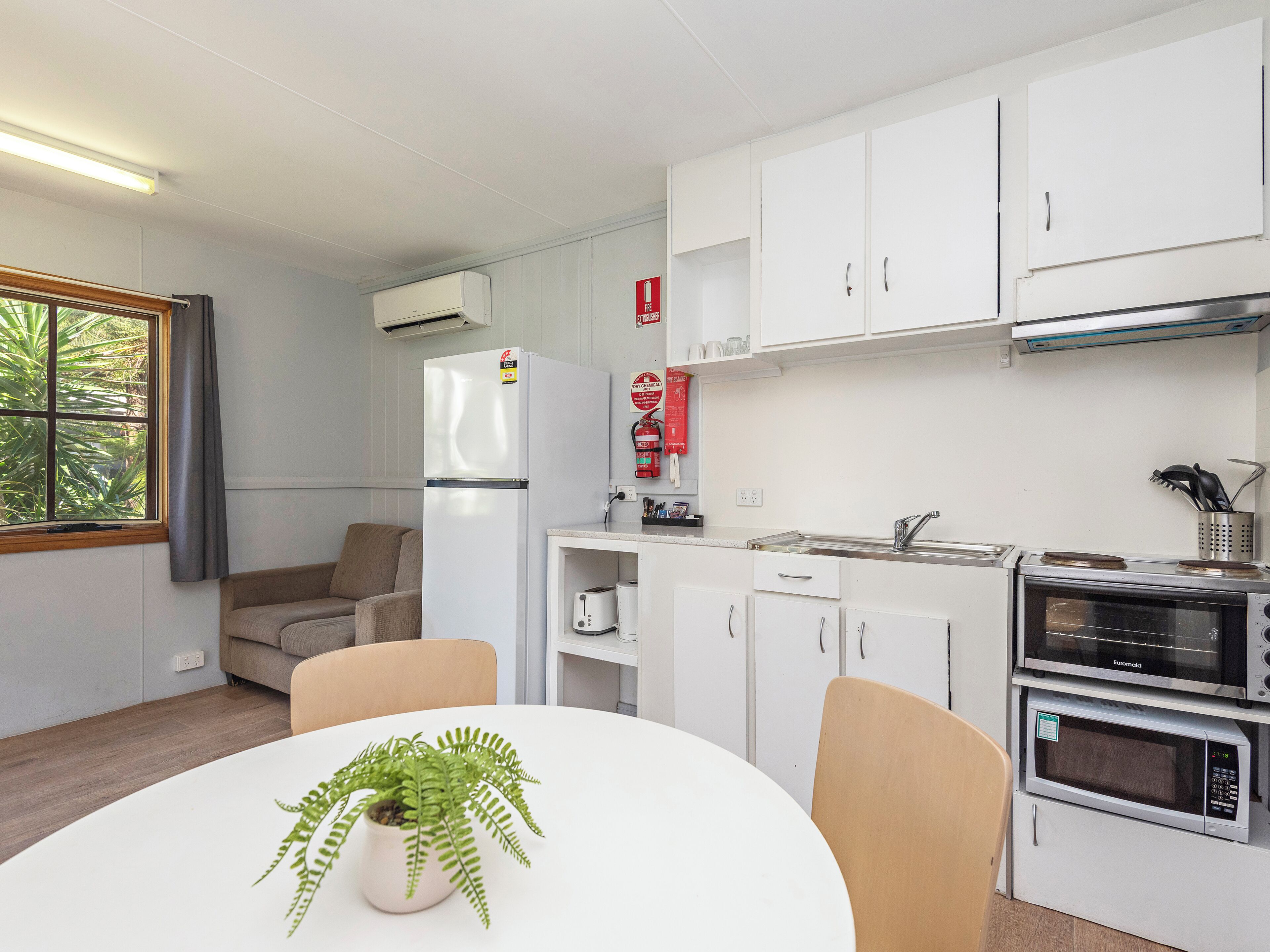 A compact kitchen with white cabinets, a built-in oven, and a dining area with a table and chairs.