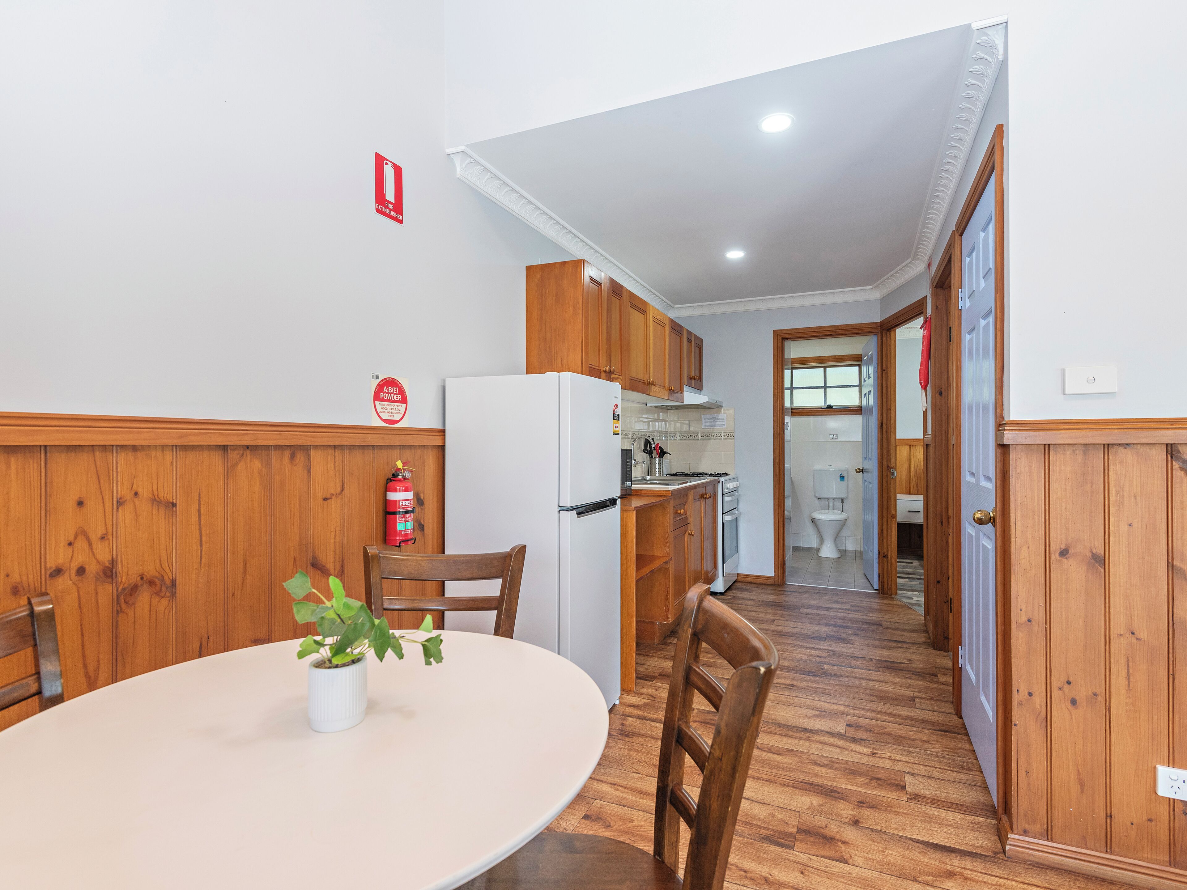 A kitchen with wooden cabinets, a white refrigerator, and a dining table with chairs.
