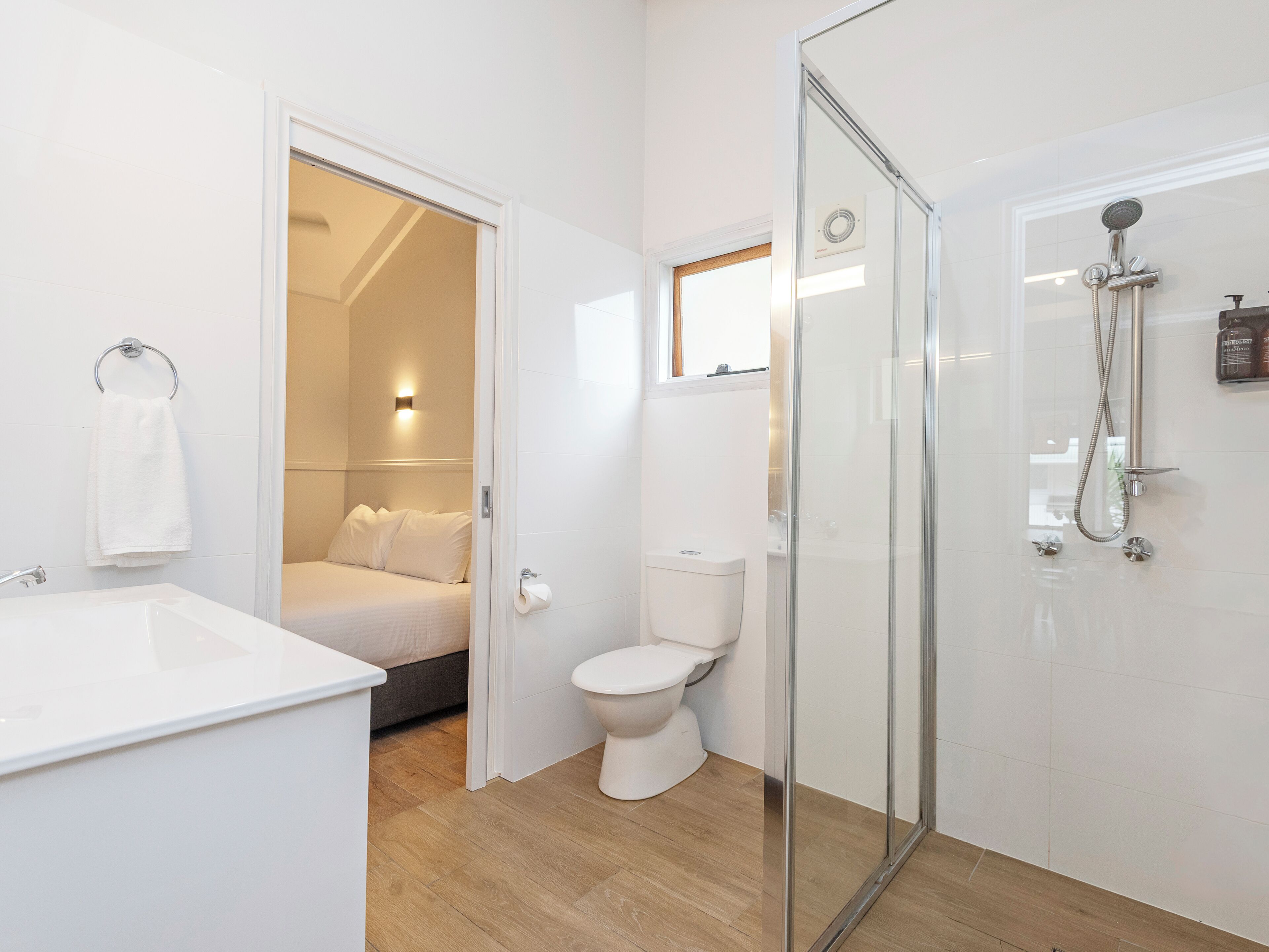 A modern bathroom with a glass shower enclosure, a toilet, and a sink.