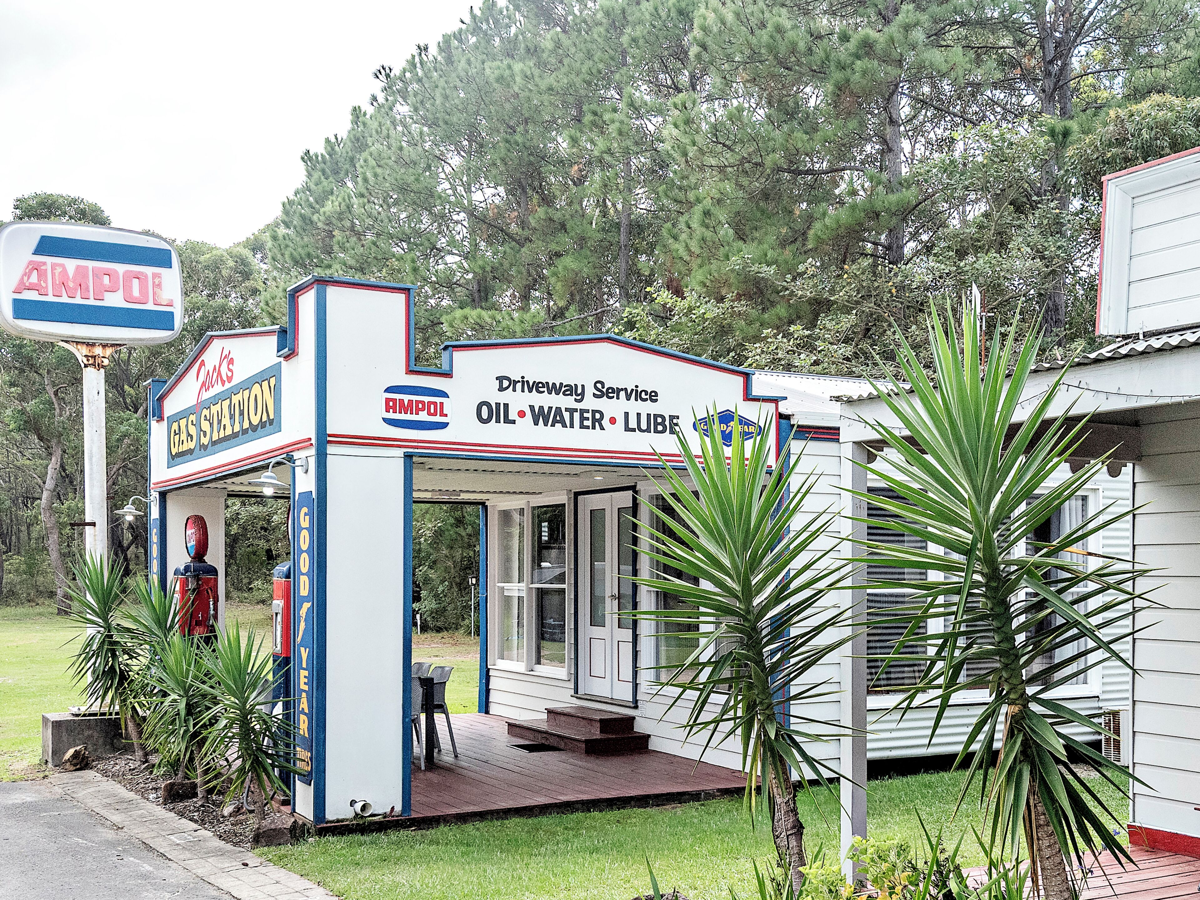 A small, single-story building with a gas station sign, a covered entrance, and a small porch area.