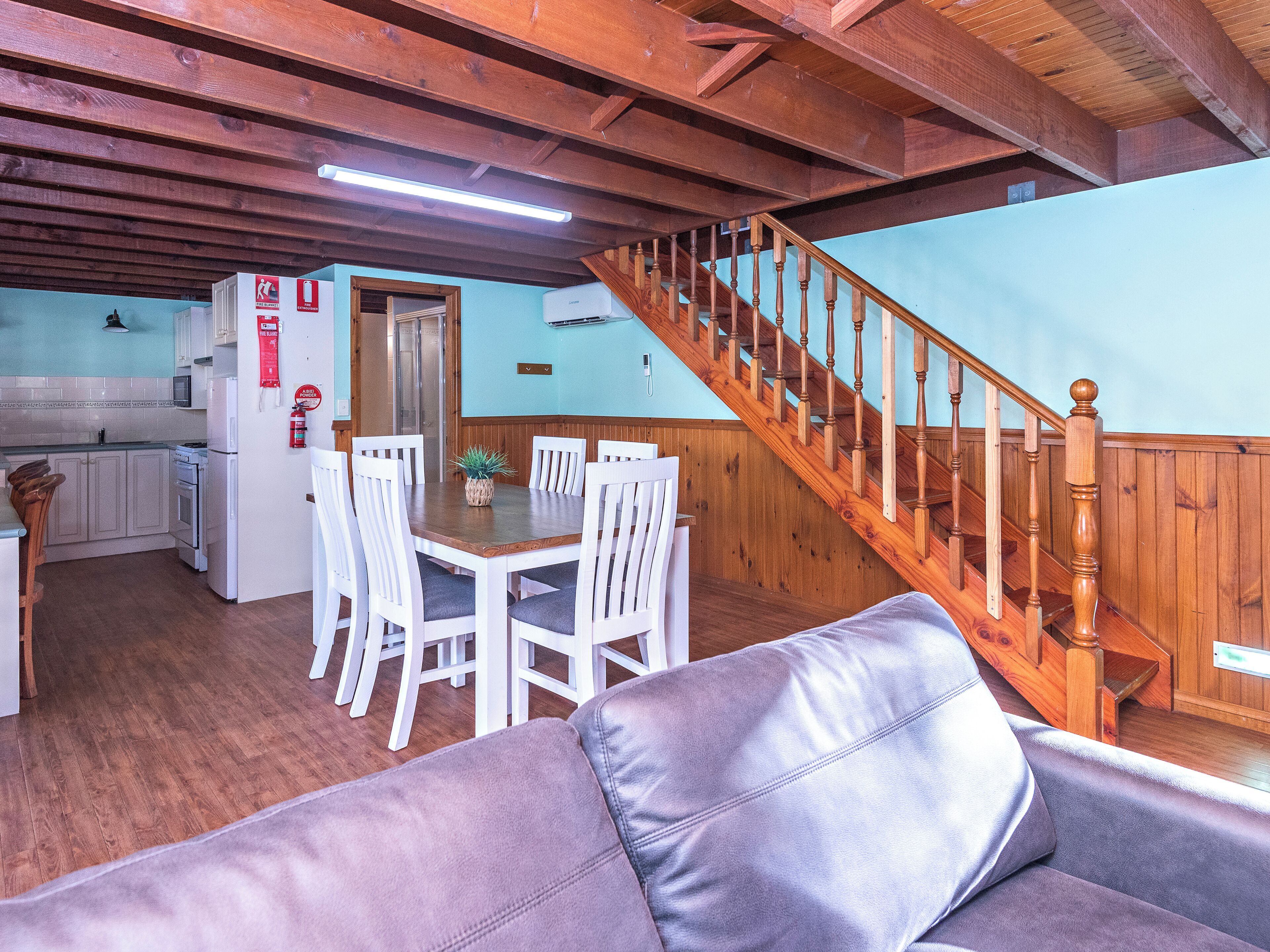 Un interior acogedor con comedor, escalera de madera y cocina.