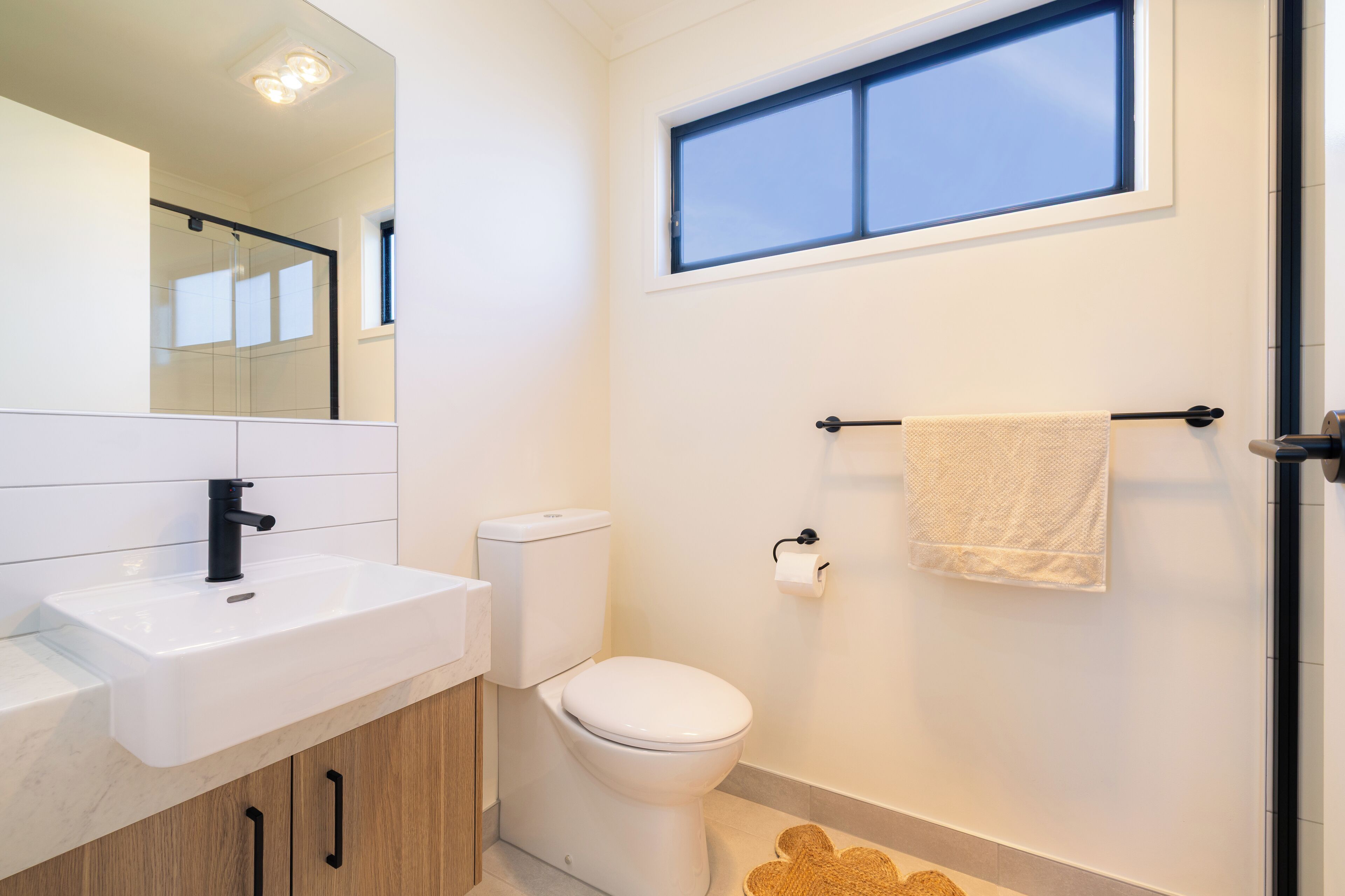 A modern bathroom with a white sink, toilet, and a towel rack.