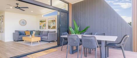 A modern living room with a sofa, coffee table, and a dining area with a table and chairs.