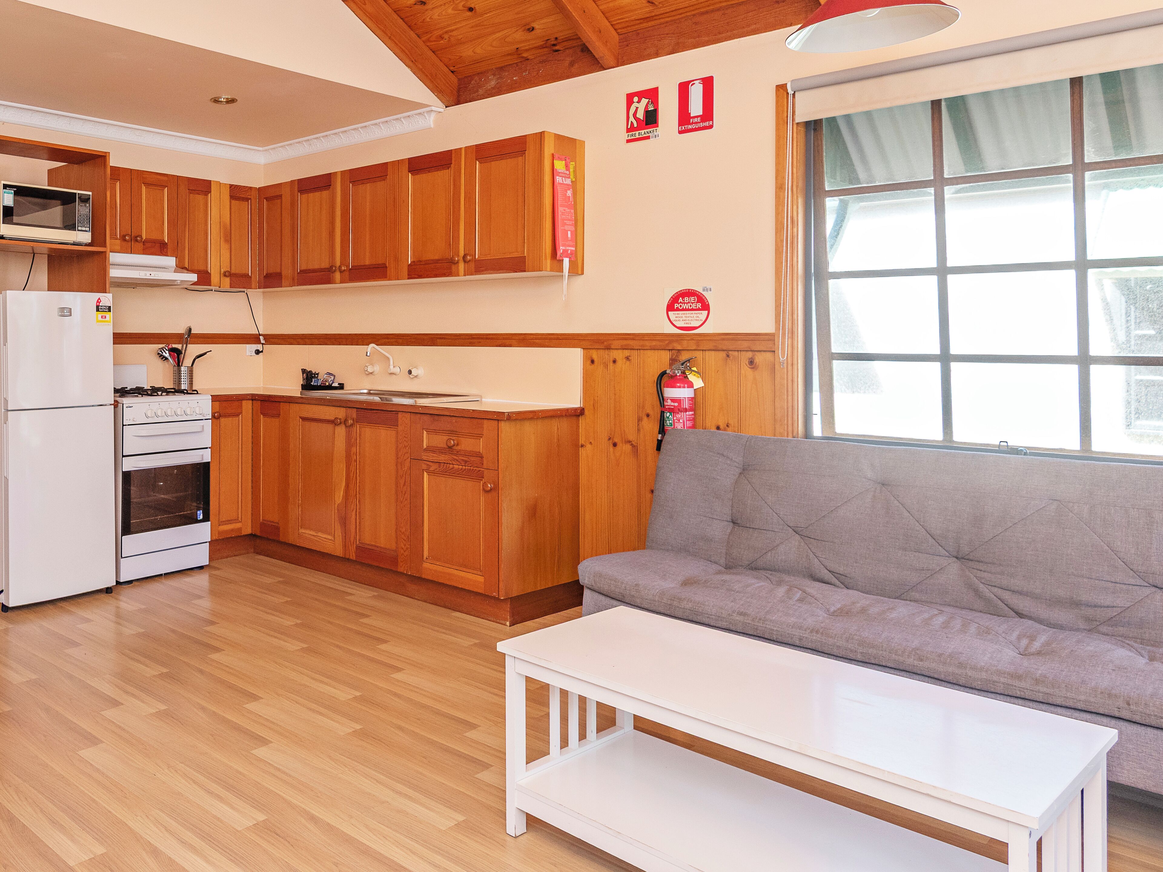 A kitchen with wooden cabinets, a white stove, and a window with a view.