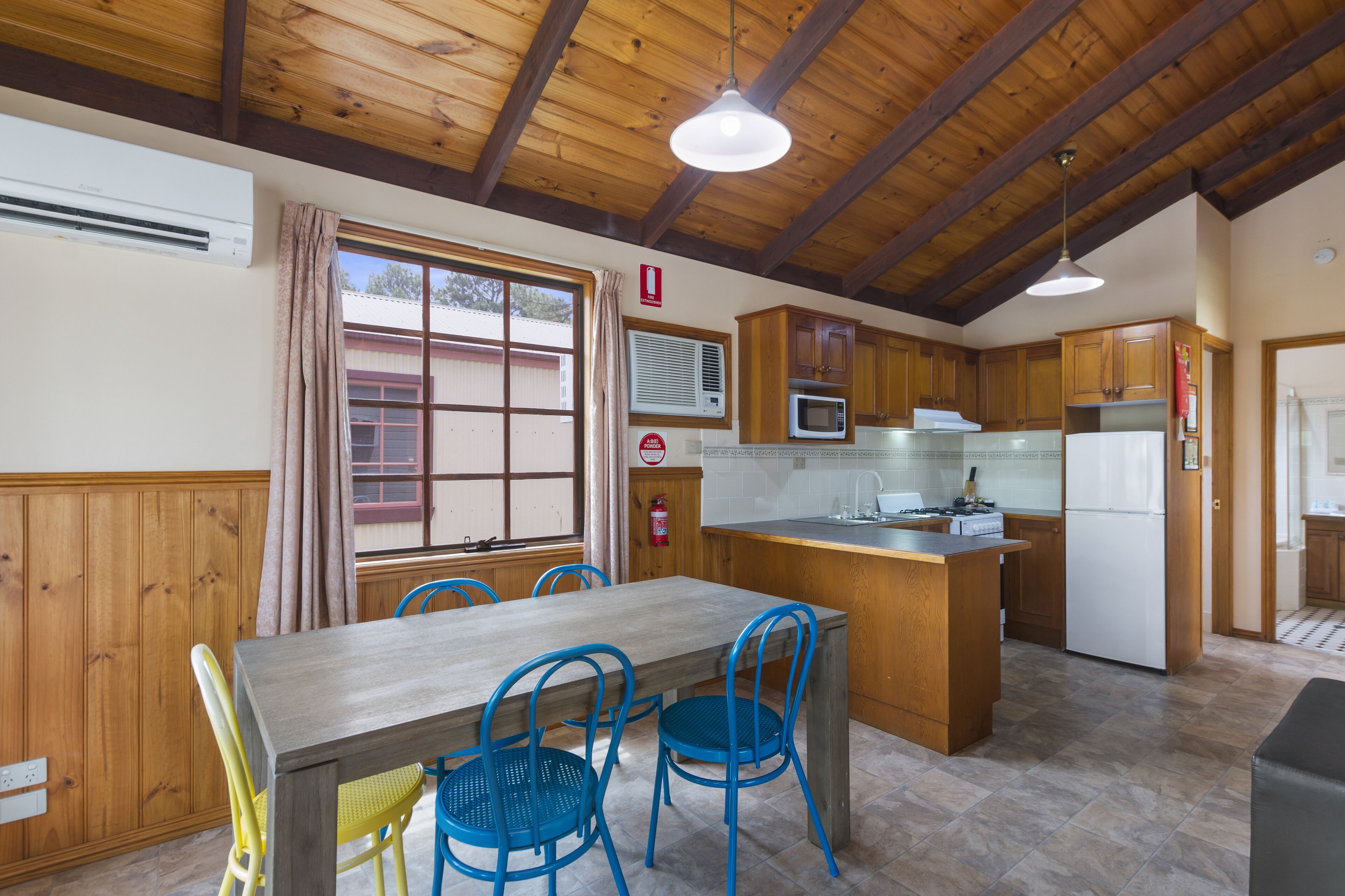 A kitchen with wooden cabinets, a dining table with blue chairs, and a built-in island with a sink.